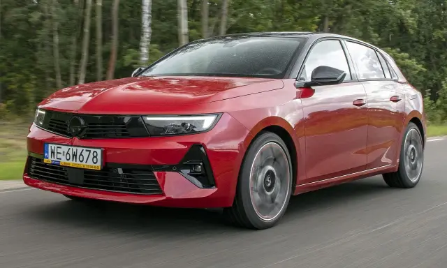 Czerwony Opel Astra Turbo pędzi leśną drogą.