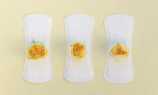 Tres compresas blancas con rosas amarillas, simbolizando un flujo amarillo antes de la regla.
