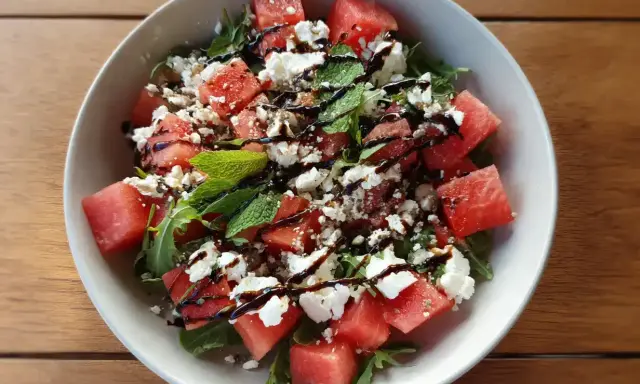 En uppfriskande sallad med tärnad vattenmelon, smulad fetaost och färsk basilika, ringlad med balsamvinäger.