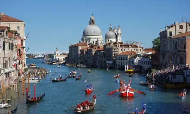 La Regata Storica anime le eaux de Venise, avec des gondoles et des bateaux traditionnels en compétition, sous le regard de la basilique Santa Maria della Salute.