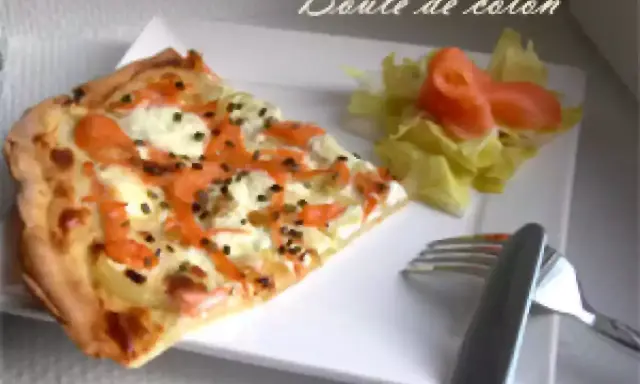 Une part de flamenkuch saumon, garnie de fromage frais et d'aneth, accompagnée d'une salade verte et de saumon fumé.