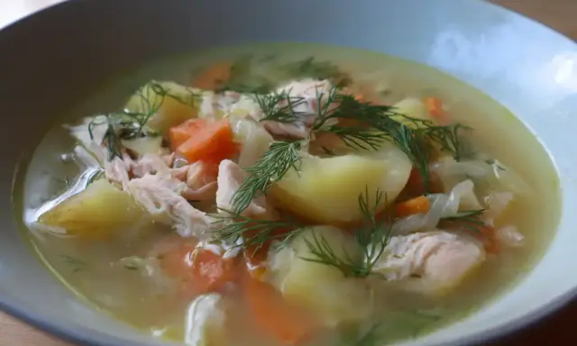 En närbild av en skål med värmande fisksoppa, full av potatis, morötter och dill. Ett perfekt fisksoppa recept för en kall dag.