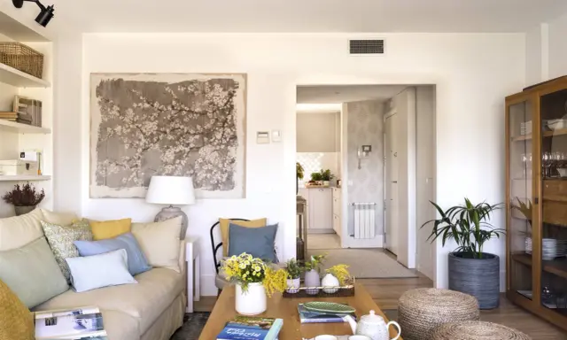 Ideas para decorar un salón moderno y elegante: sofá beige, mesa de centro de madera, arte floral, plantas y detalles acogedores.