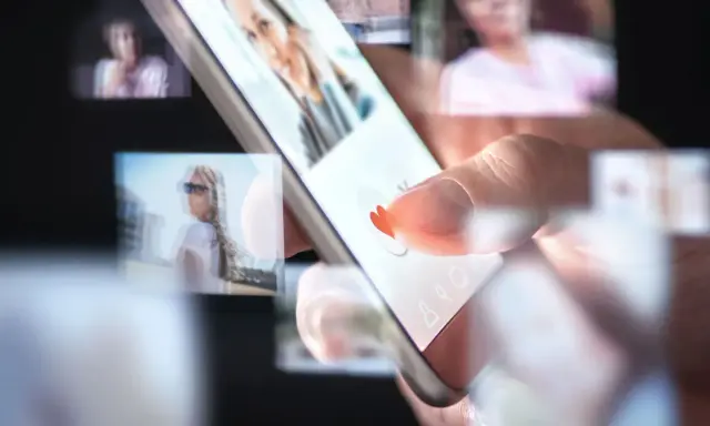 Palec przesuwa po ekranie smartfona, wybierając potencjalnych partnerów w aplikacjach randkowych.