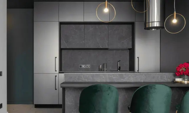 Cuisine moderne avec armoires grises, îlot en marbre et suspensions dorées. Pour un éclairage optimal, combien de lumen pour une cuisine ?