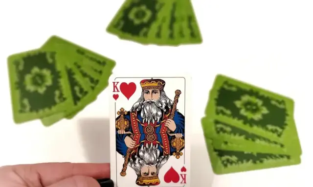 Król kier, a za nim stos zielonych kart. Czyżby to była gra w "Dupa biskupa"?