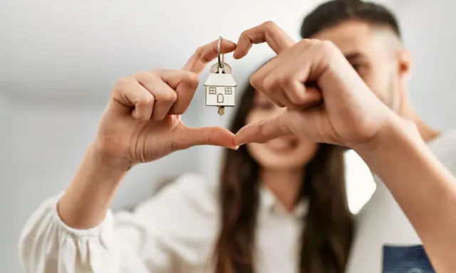 Un couple non marié célèbre son achat maison. Les mains forment un cœur autour de la clé, symbole de leur nouveau foyer, un nouveau départ après un décès.