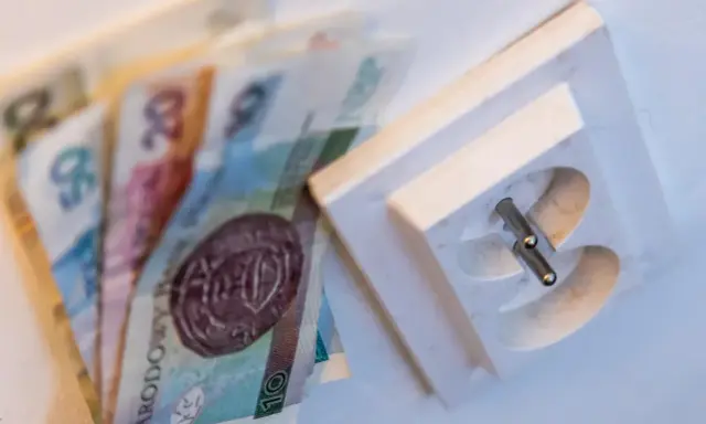 Pieniądze leżą obok gniazdka elektrycznego. Czy to symbolizuje pge brak faktury i rachunków do zapłaty?