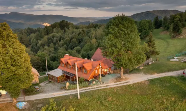 Malowniczy dom z czerwonym dachem w otoczeniu zielonych wzgórz. Idealne miejsce na agroturystykę w Pieninach, gdzie można odpocząć od zgiełku.