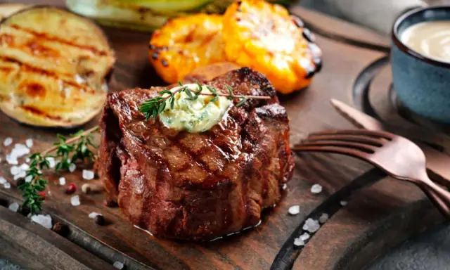 Perfekt gegrilltes Fleisch mit Kräuterbutter, dazu gegrilltes Gemüse und eine Dip-Schale.