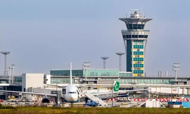 Wieża kontroli lotów i samoloty na jednym z lotnisk w Paryżu.