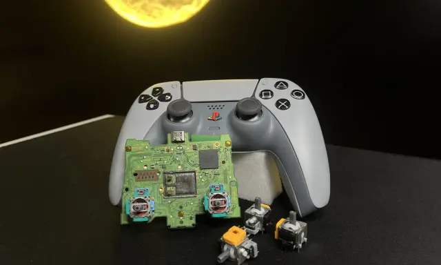 Na zdjęciu widać rozłożony kontroler DualSense z płytką drukowaną i kilkoma joystickami.