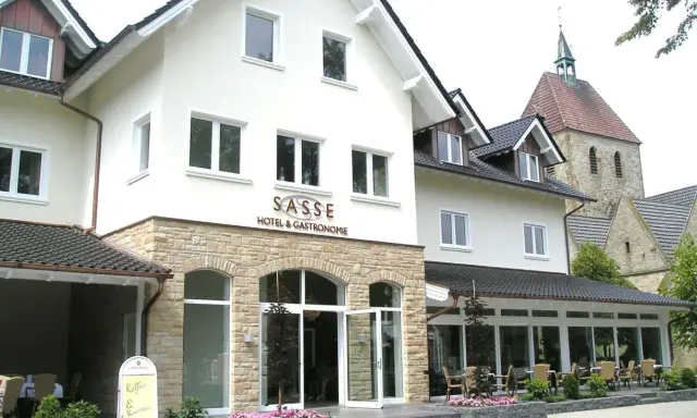 Gasthof Sasse in Soest mit Hotel & Gastronomie-Schild, Steinfassade und Kirche im Hintergrund.