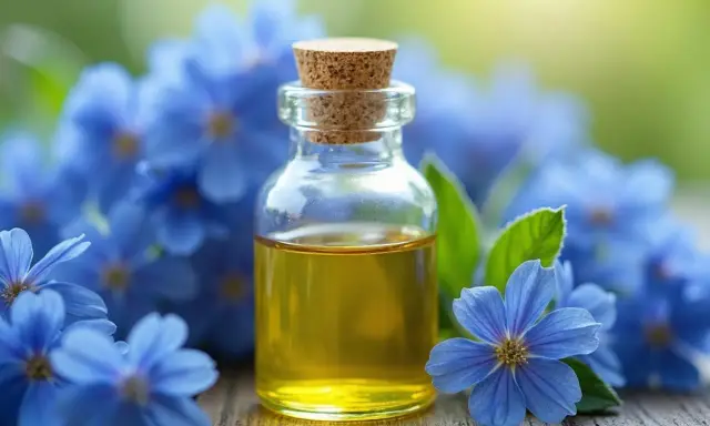 Flacon d'huile de bourrache aux multiples bienfaits, entouré de fleurs bleues délicates sur fond vert.