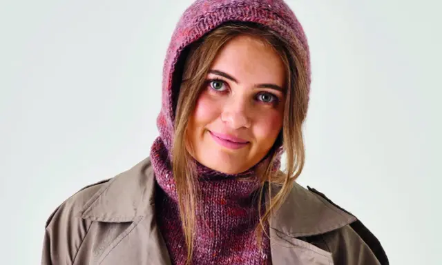Ung kvinna med stickad balaclava i rosa toner och en beige kappa. Perfekt för barn som vill sticka en egen balaclava.