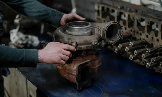 Mechanik trzyma turbosprężarkę, przygotowując się do wymiany zaworu N75.