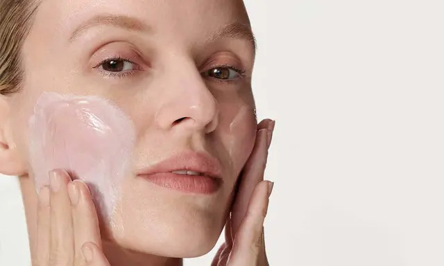 Donna applica delicatamente crema viso con le dita, un gesto semplice per prendersi cura della pelle.