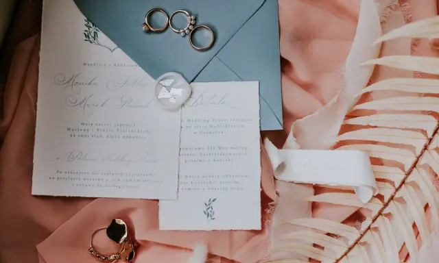 Eleganckie wypisywanie zaproszeń ślubnych z obrączkami i pieczęcią lakową.