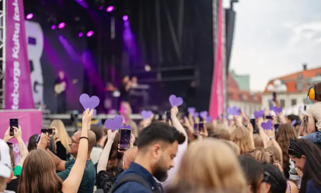 Publik med lila hjärtan och mobiler fångar en konsertupplevelse under ett av Göteborgs evenemang.