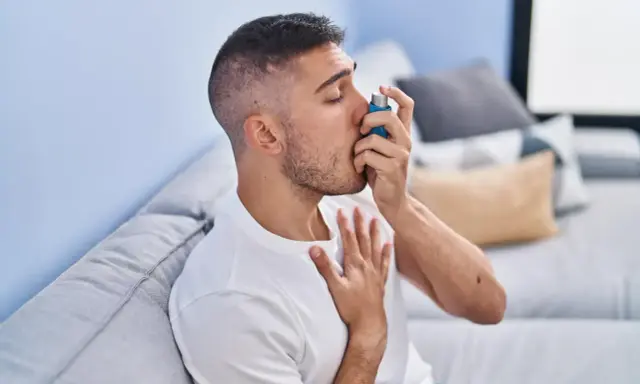 Mężczyzna używa inhalatora, szukając ulgi w objawach astmy. Leki na astmę bez recepty mogą pomóc w łagodzeniu napadów.