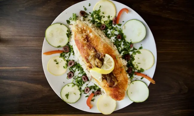 Ryba z ryżem, cytryną, oliwkami i warzywami. Pyszne danie w stylu dieta śródziemnomorska.