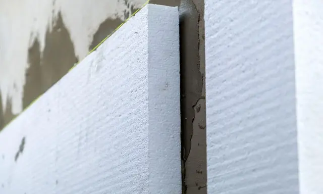 Aislamiento de poliestireno expandido en una pared, paso clave para **edificios eficientes** y confortables.