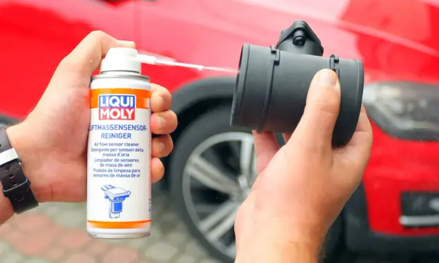 Czyszczenie przepływomierza preparatem Liqui Moly. W tle czerwony samochód.