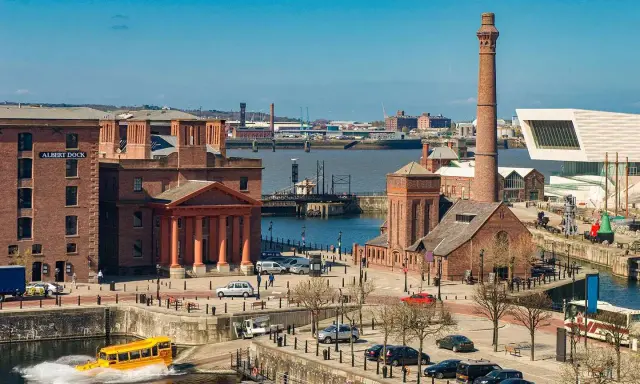 Albert Dock in der Liverpool Stadt, mit einem gelben Amphibienfahrzeug im Wasser und einem hohen Schornstein.