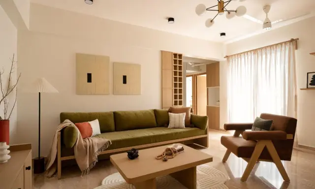 Soggiorno in stile Japandi con divano verde, poltrona in pelle, tavolino in legno e opere d'arte minimaliste.