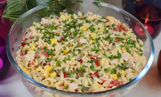 Pyszna sałatka z makaronem orzo, kukurydzą, papryką i kurczakiem, posypana szczypiorkiem. Idealna na letnie dni.