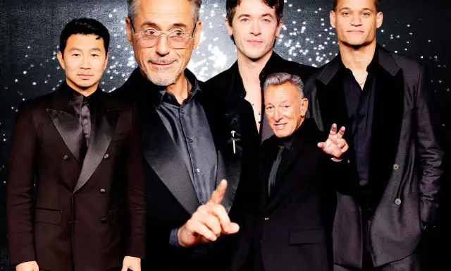 Five men in black suits with black shirts pose for a photo.