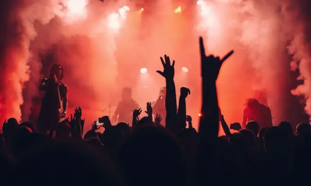 Tłumy na jednym z corocznych festiwali w Polsce, wznoszą ręce w górę, otoczone dymem i czerwonym światłem sceny.
