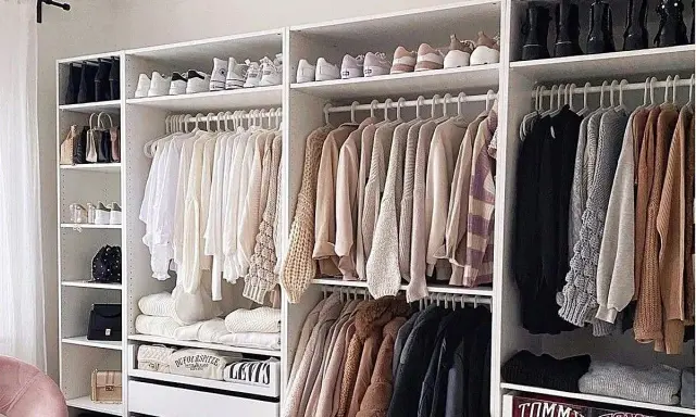 Armarios blancos perfectamente organizados con ropa y zapatos ordenados. Un ejemplo de cómo organizar armarios para un espacio funcional y estético.