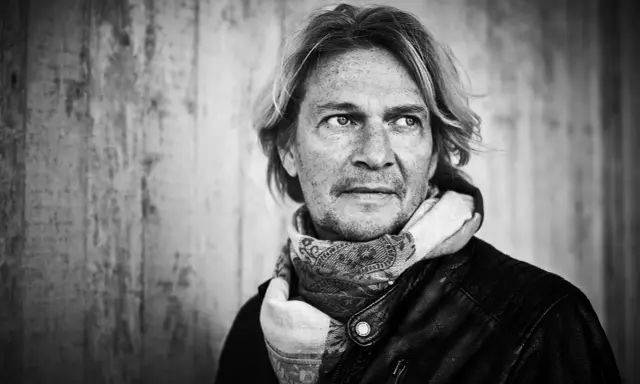 Tommy Nilsson, med sitt karaktäristiska utseende och en scarf, redo att inta scenen med sitt band.