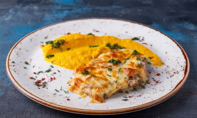 Schab po zbójnicku z purée z dyni, posypany zieloną pietruszką i czerwonym pieprzem.