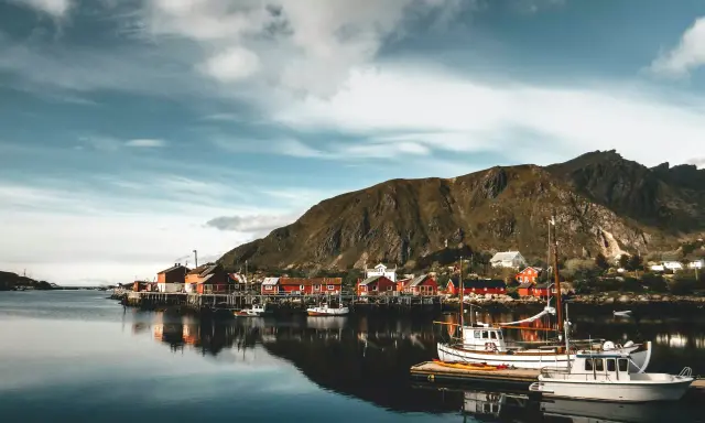 Malowniczy norweski port z czerwonymi domkami i łodziami. Czy do Norwegii trzeba mieć paszport? Sprawdź przed podróżą!