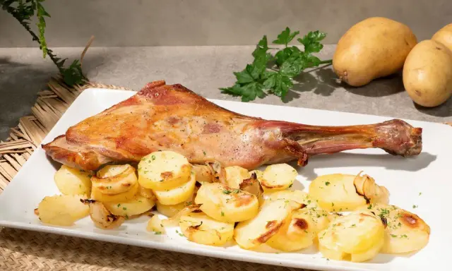 Paletilla de cordero al horno dorada y jugosa, acompañada de patatas panadera y perejil fresco. Un plato principal delicioso.