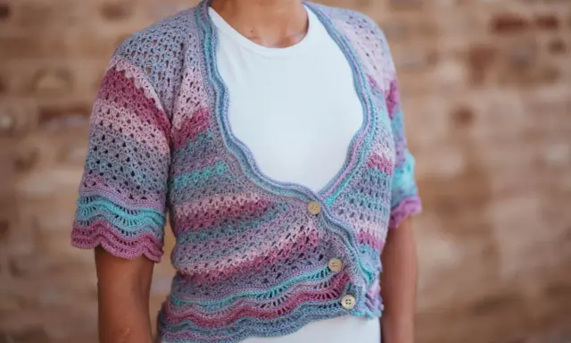 Chaqueta de crochet con rayas degradadas en tonos pastel y delicados puntos calados. Tres botones de madera cierran la prenda.