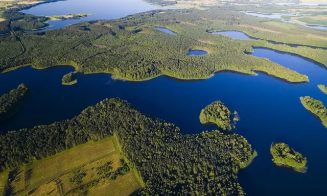 Malownicze jeziora na Mazurach otoczone gęstymi lasami, z widokiem na pola i dalsze akweny.