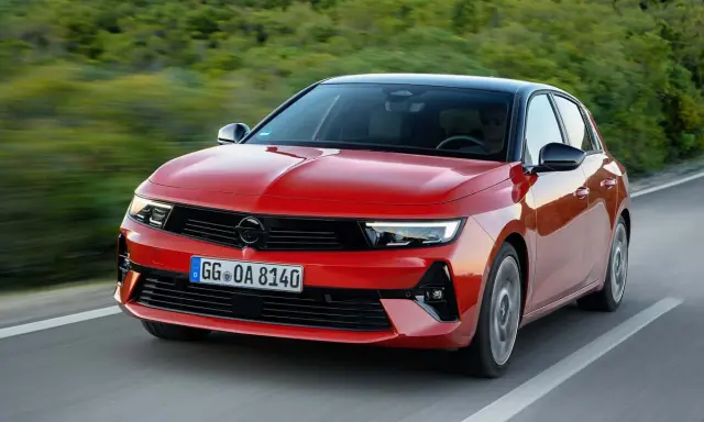 El nuevo Opel Astra rojo, con techo negro, circula por una carretera sinuosa rodeada de vegetación.