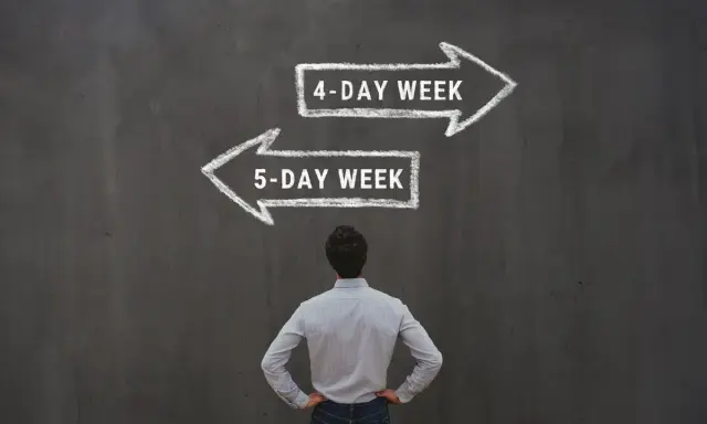 Mężczyzna stoi przed tablicą, na której kredą narysowano dwie strzałki: w prawo "4-DAY WEEK" i w lewo "5-DAY WEEK".