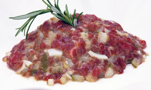 Delicioso steak tartar de los Hermanos Torres, con carne picada, cebolla, pepinillos y un toque de romero.