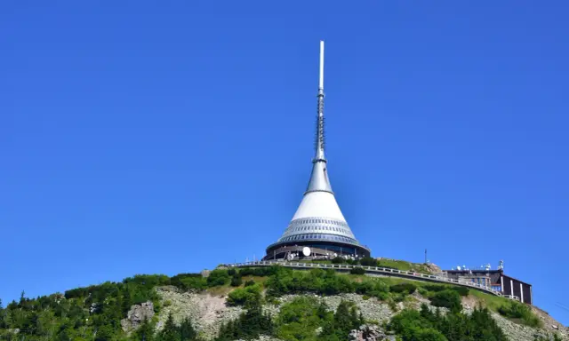 Wieża telewizyjna Ještěd, jedna z głównych libereckich atrakcji, góruje nad zielonym wzgórzem.