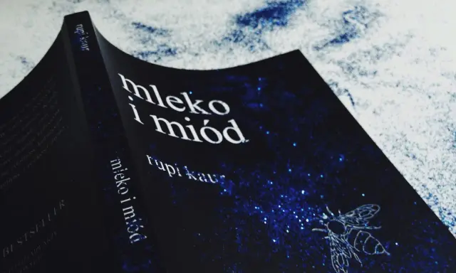Okładka książki "Mleko i miód" Rupi Kaur z motywem pszczoły na granatowym tle w gwiazdy.
