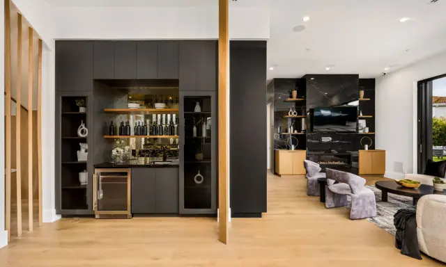 Elegante angolo bar in casa con bottiglie, cantinetta e mensole a vista.