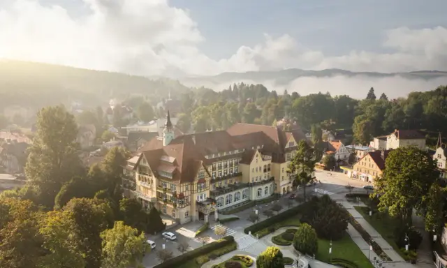 Sanatorium Polonia w Kudowie Zdroju, z pięknymi pokojami i otoczeniem, w mglisty poranek.
