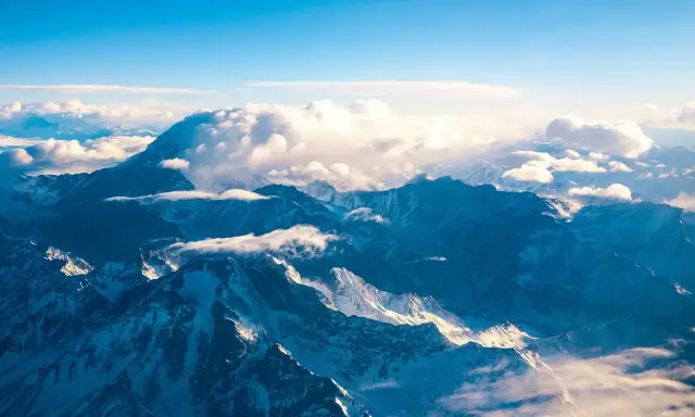 Majestatyczne góry z Aconcagua, skąpane w słońcu, otoczone chmurami. Widok z lotu ptaka na ośnieżone szczyty.