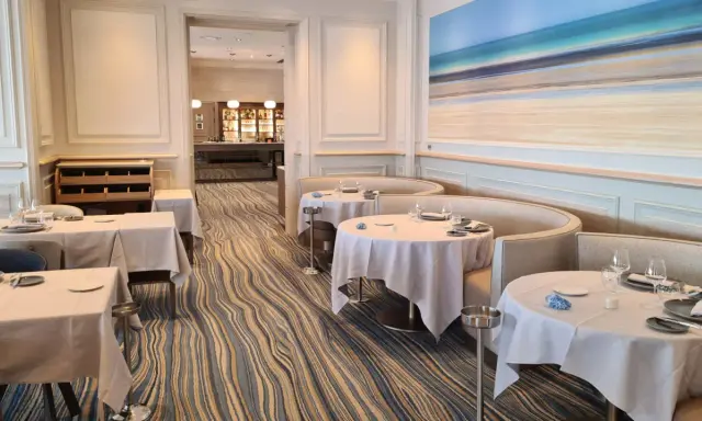 Élégant bistro à Saint-Malo, tables dressées, ambiance chic avec une fresque marine au mur.