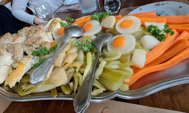 Plat généreux d'un restaurant du terroir : viandes, légumes racines et légumes verts, prêt à être dégusté.