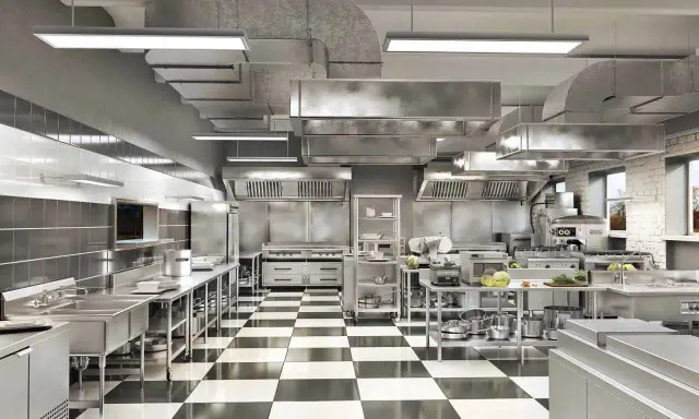 Cocina profesional de acero inoxidable con suelo de baldosas a cuadros, campanas extractoras y equipamiento listo para cualquier tipo de cocina.